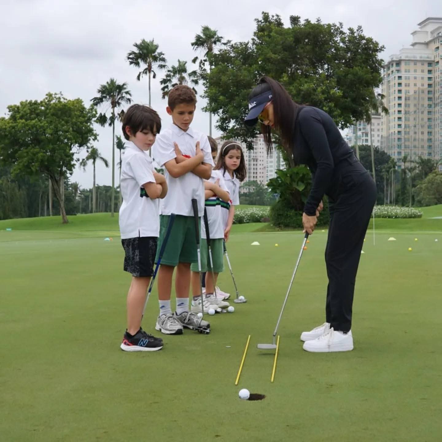 Rukmini Mehta demonstrating a putt to four junior students on a putting green