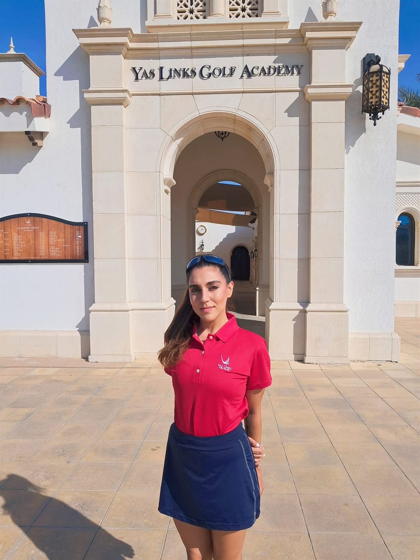 Rukmini Mehta standing at the entrance of the Yas Links Golf Academy, Abu Dhabi