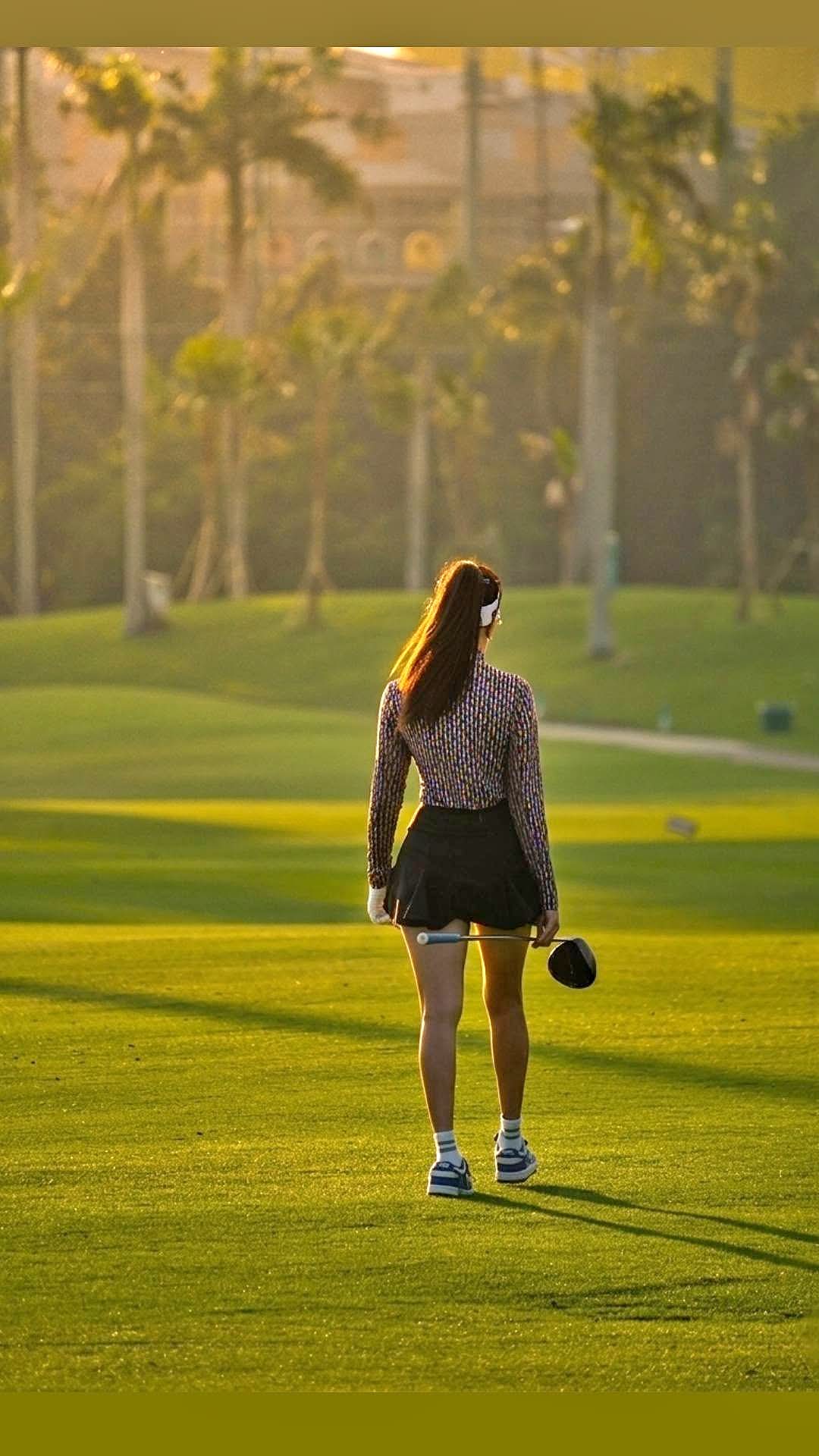 Rukmini Mehta walking down a sunlit palm-lined fairway at golden hour carrying a driver